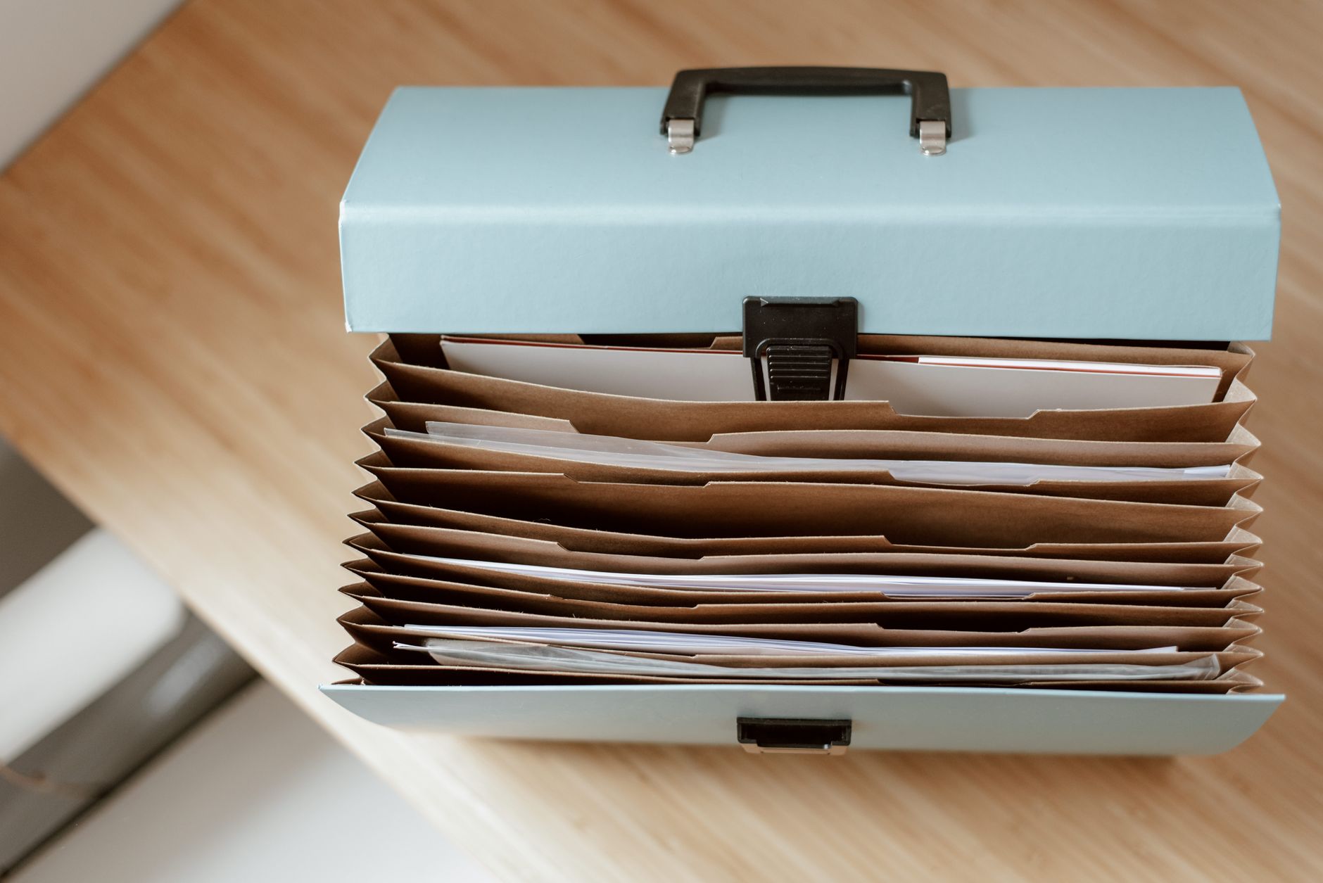Mains posées sur une table avec un dossier de documents administratifs et un stylo.
