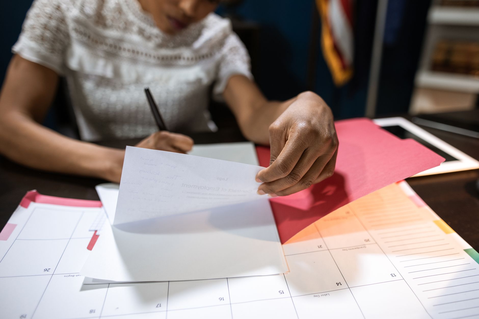 Un calendrier mural et une pochette de dossier posés sur un bureau, près d'une enveloppe.